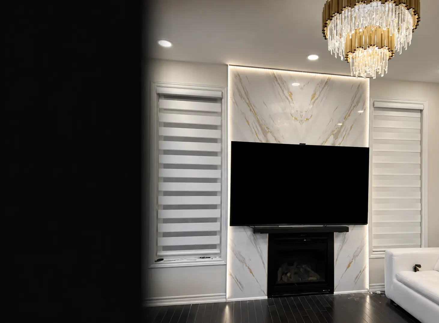 Finished illuminated feature wall with marble-look surround, television, fireplace and gold chandelier